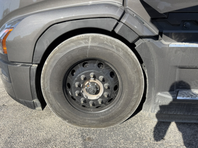 Truck front wheel showing black steel rim and tire with hub and lug nuts.