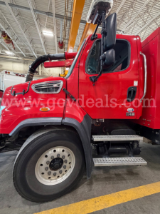 Freightliner 114SD truck cab side showing front wheel, red exterior, steps, and side mirror.