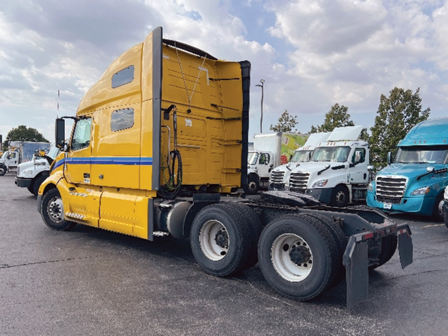 Volvo VNL 760 truck tractor in yellow with blue stripe, side view showing sleeper cab and chassis.