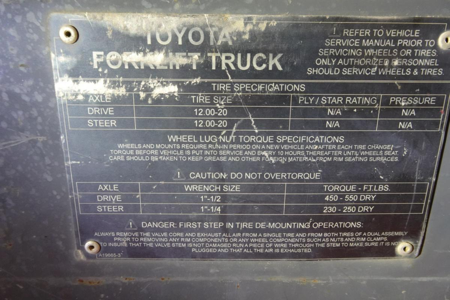 Toyota forklift truck data plate showing axle, drive, steer, tire specifications and torque; includes warnings and numbers such as 12.00-20 tire size, 1-1/2 inch wrench size, 450-550 ft-lbs torque, 230-250 dry? in fuel