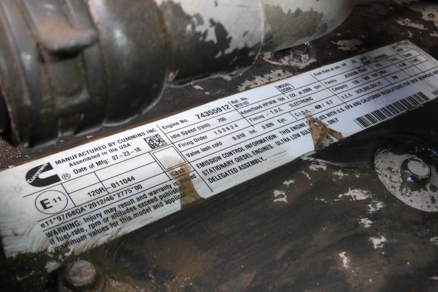 Label on forklift equipment showing serial and approval information with a barcode and various small text blocks.