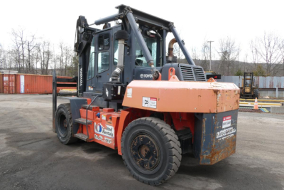 Truck-mounted forklift 2018 Toyota THD3000-24 in serviceable condition showing cab, orange counterweight, and forklift mast in a yard.