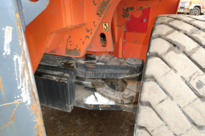 Truck crane/lift base showing hydraulic battery compartment and heavy tire on the right side.