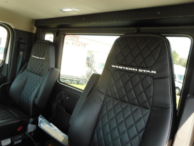Interior of a Western Star 49X cab showing quilted black leather seats with ‘WESTERN STAR’ embroidery; windows and cabin area visible.