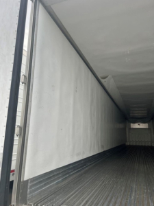 Trailer interior showing empty refrigerated trailer with smooth white side walls and ribbed metal floor.