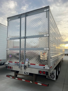 Trailer rear view showing diamond plate aluminum refrigerated trailer with doors and brake/marker lights.