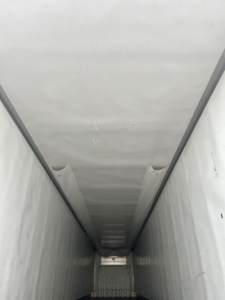 Trailer interior showing a long refrigerated cargo area with white walls and ceiling, painted metal floor, no visible labels or text inside.