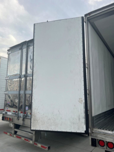 Refrigerated trailer rear door and open side showing interior cargo area and hinges.