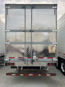 Refrigerated trailer rear view with diamond plate aluminum doors and dual rear lights. Appears used; stock U91140 with side door latches and warning stickers visible.