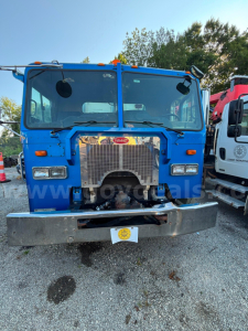 Truck front view showing large radiator grille, headlights, and bumper of a blue 2010 Peterbilt COE truck.