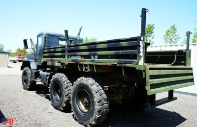 Truck bed view of a 1990 BMY 14 military truck showing dual rear wheels and camo flatbed with side rails.