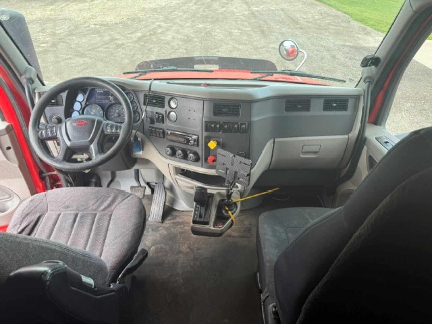 Conventional sleeper tractor interior showing dashboard, steering wheel, and center console in a Peterbilt truck cab.