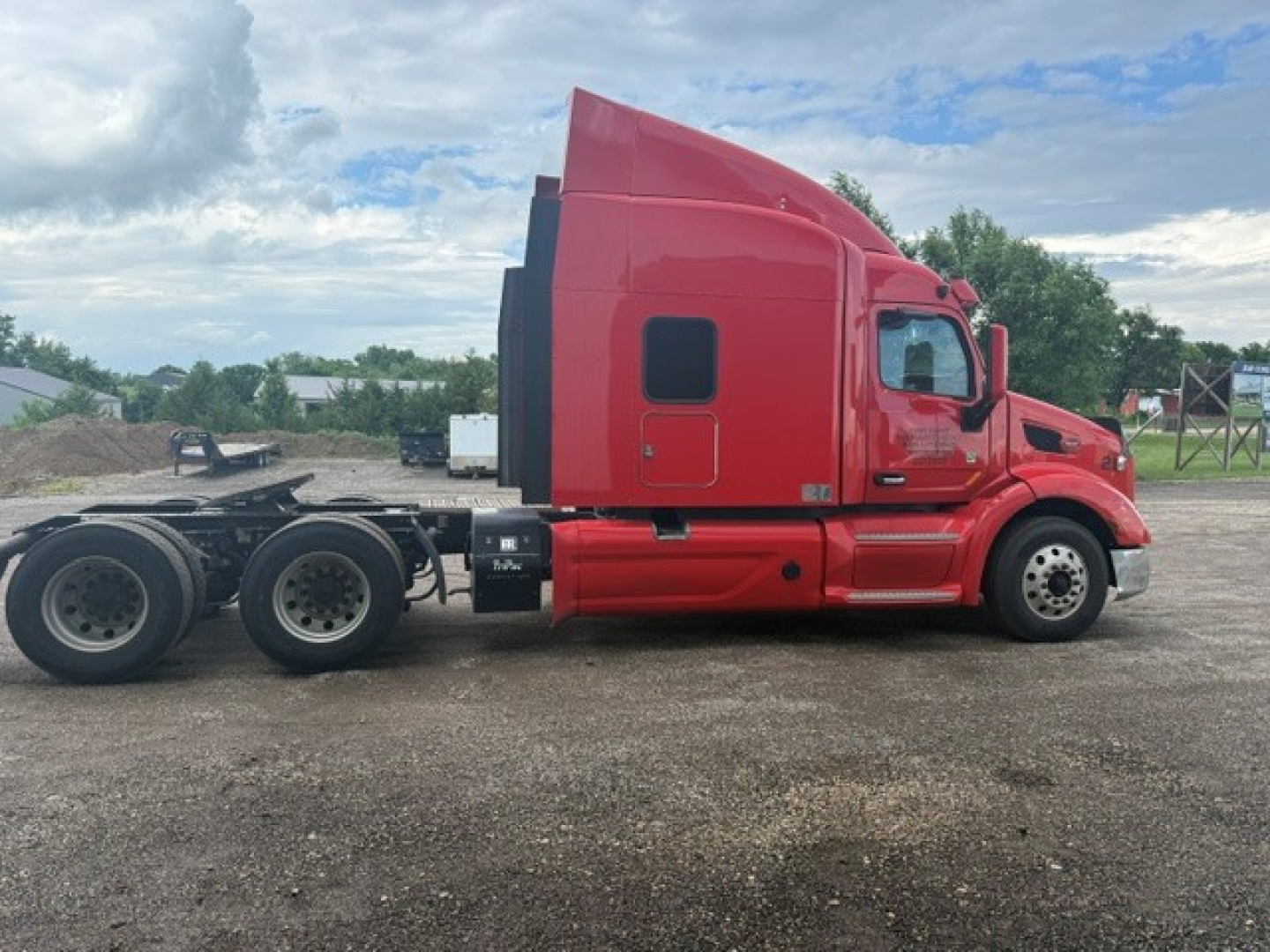 Peterbilt 579 tractor in side profile view, red cab with sleeper, dual rear axles, no trailer connected.