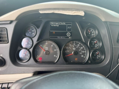 Peterbilt 579 dashboard showing gauges and central display with warnings, RPM and speed gauges visible.