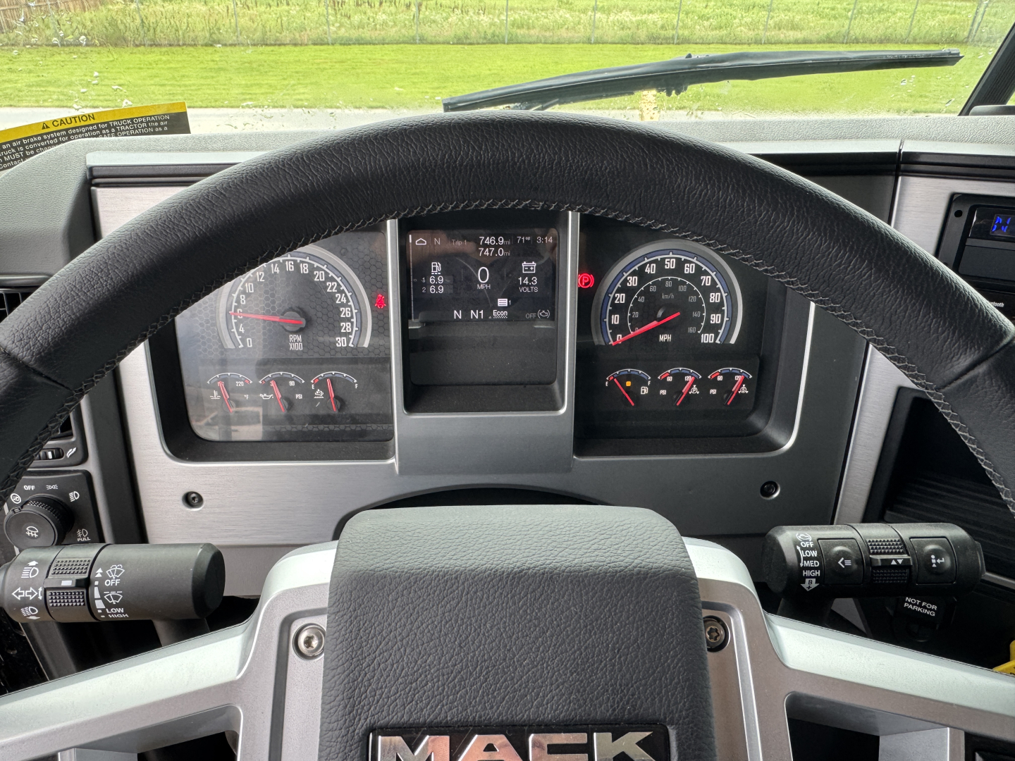 Dashboard view of a 2025 Mack GR104F truck showing steering wheel, instrument cluster, digital display, and control stalks.