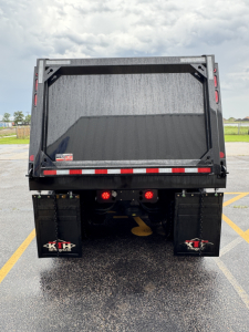 Dump truck bed rear showing two K&H mud flaps and tail lights.
