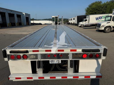 Flatbed trailer rear view showing taillights, bumper, and license plate area. Visible text includes UAB 351 on plate area, 262 on right bumper, and reflective red/white strips.