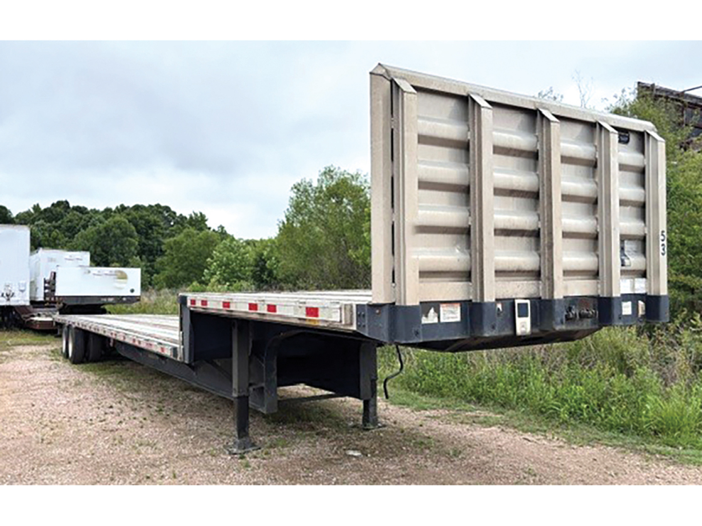 Great Dane drop deck trailer in field showing aluminum and steel composite bed and raised gooseneck with support legs visible.