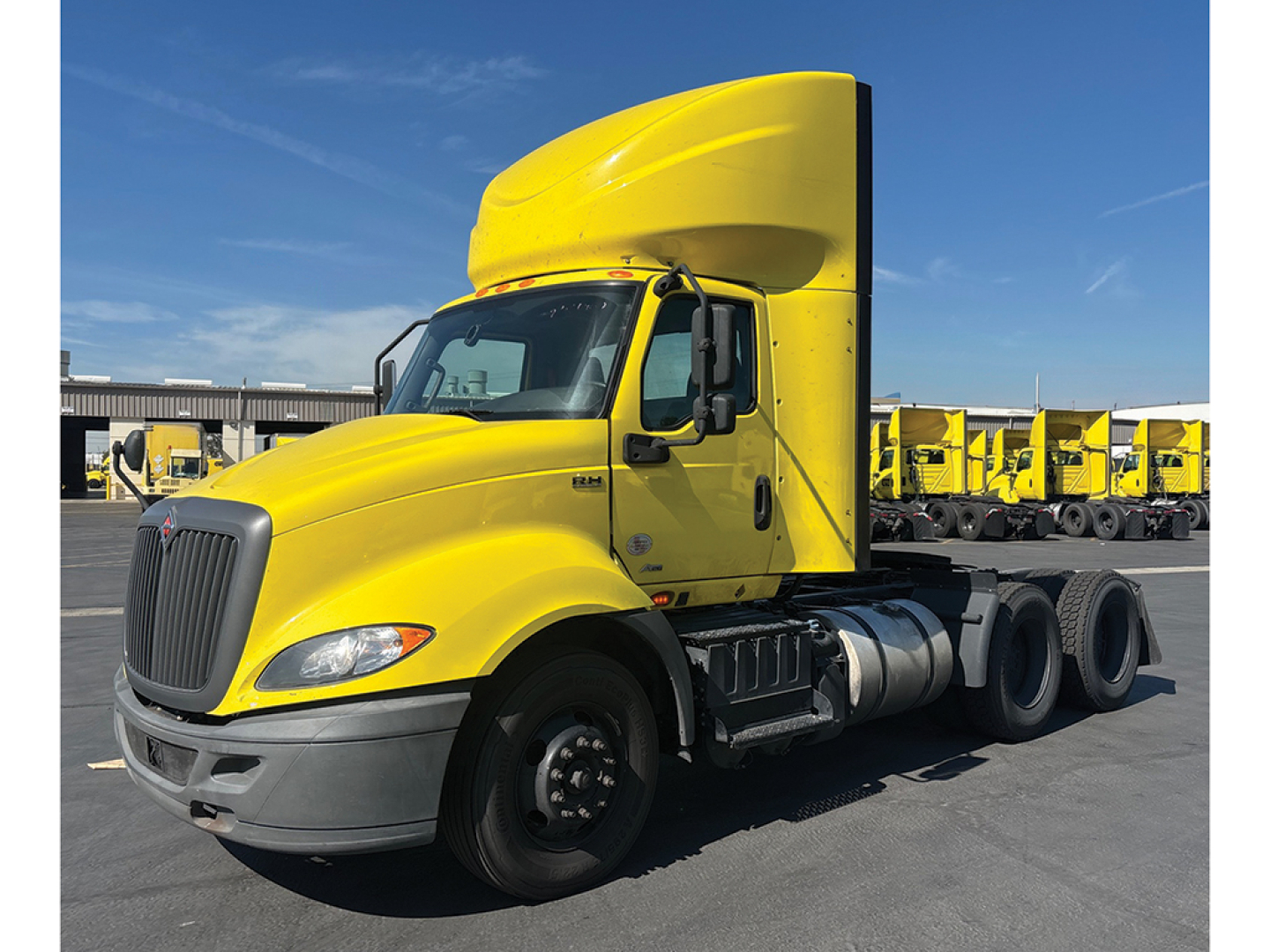 International RH613 tractor with bright yellow cab and sleeper, side view showing dual rear axles and fuel tanks.