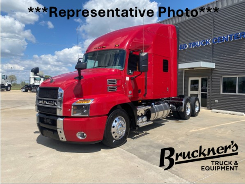 Mack AN64T70 tractor unit in red, front-left view, with black grille and chrome bumper, parked at dealership lot.