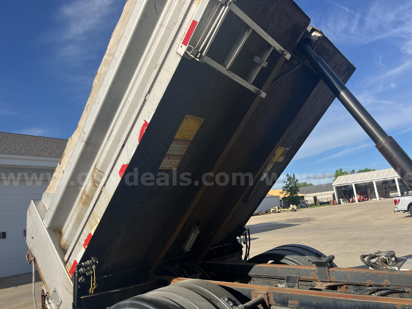 Truck bed tilt mechanism of a 2012 Hino 338 dump truck showing hydraulic lift and side panels.