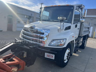 Hino 338 dump truck front-left view showing chrome grille, headlights, side mirrors, and dump bed with warning lights.