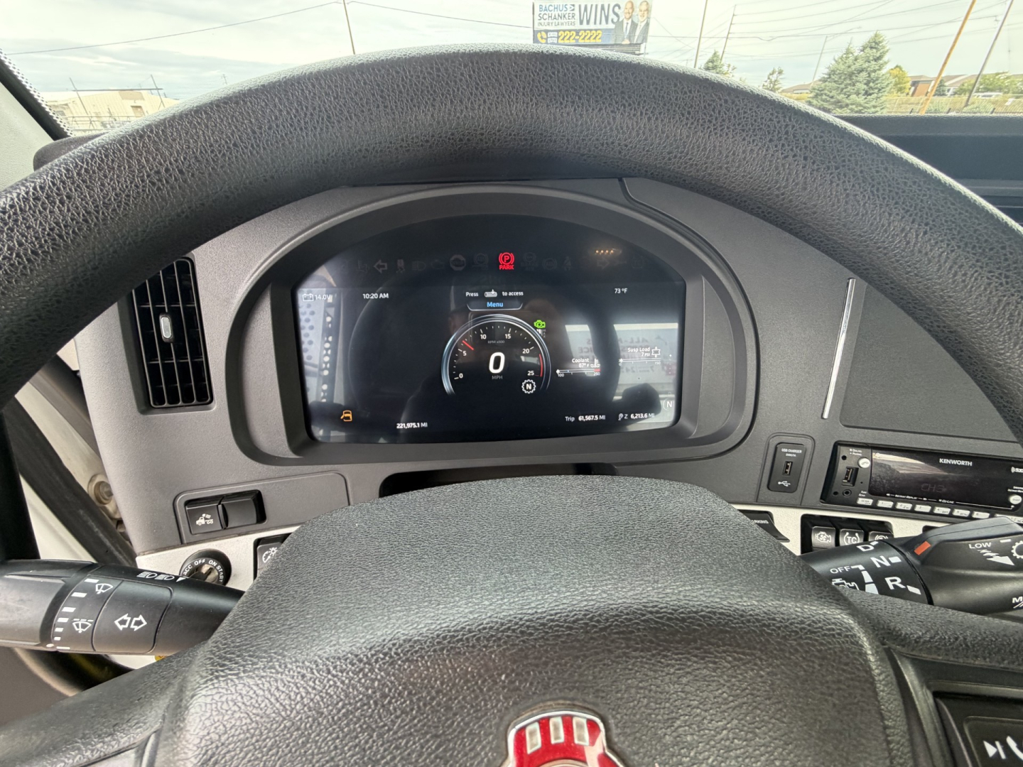 Kenworth truck cockpit with digital gauge cluster and steering wheel; various controls; dashboard text not fully legible.
