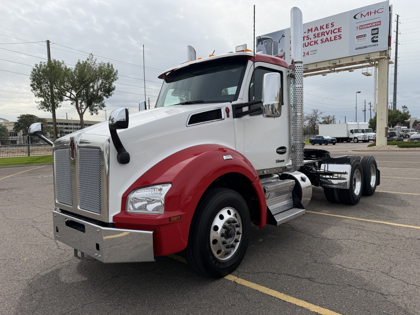 Kenworth T880 heavy truck cab in white and red, front-left view showing grille, bumper, and daytime running lights.
