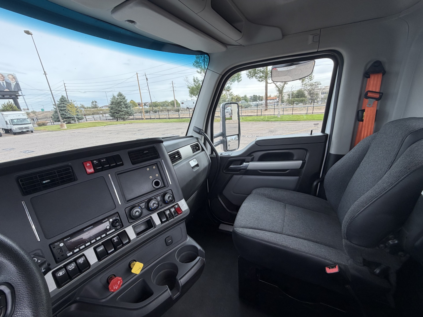 Cab interior of a 2023 Kenworth T880 conv daycab showing dashboard controls, steering wheel, and passenger seat.