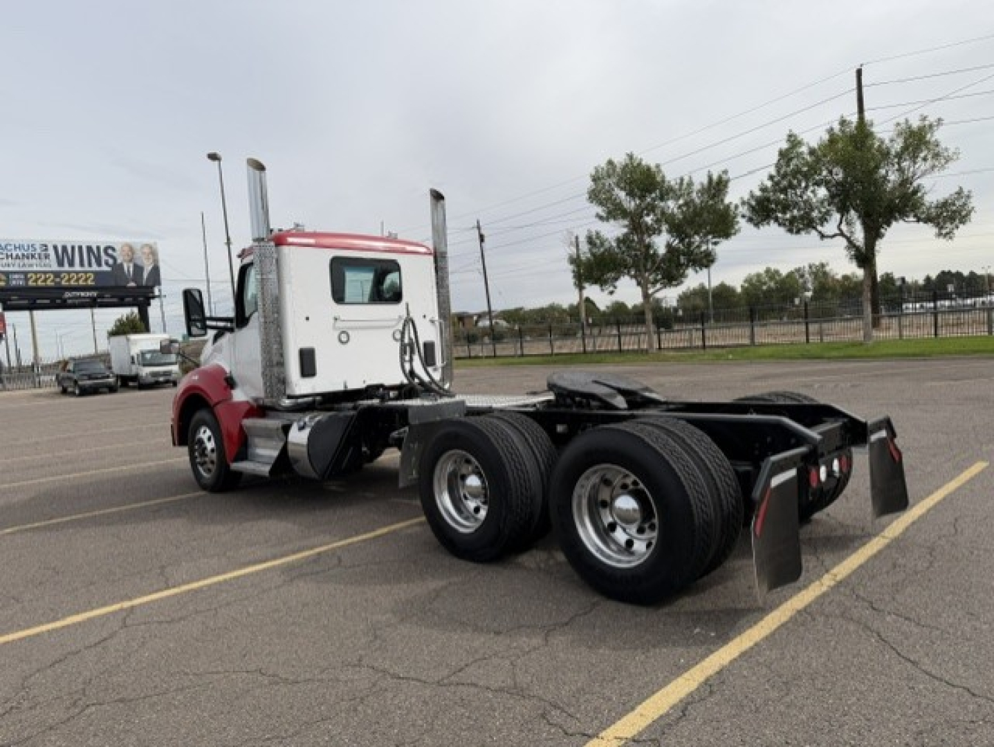 Kenworth T880 tractor rear/side view showing tandem rear axles and fifth wheel mounting, with cab in red and white.