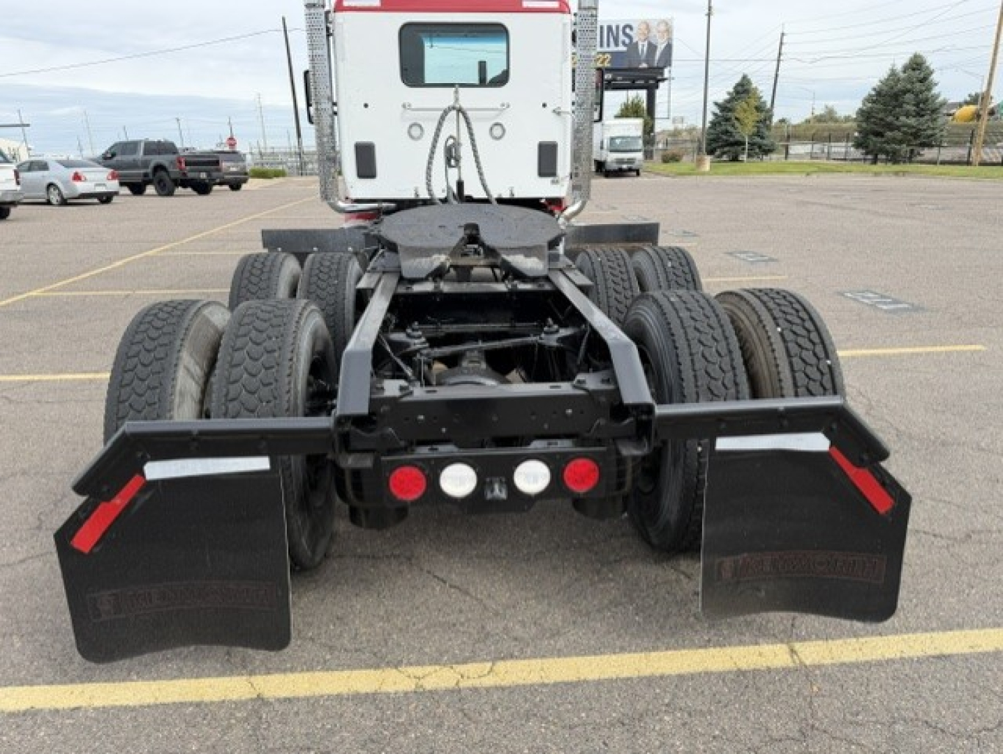 Kenworth T880 tractor rear view showing dual rear wheel configuration and black mud flaps.