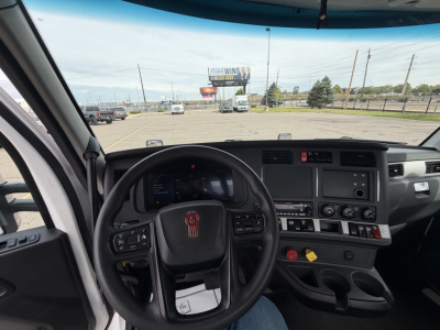 Interior view of a 2023 Kenworth T880 cab showing steering wheel, dashboard, and center console with controls and media display.