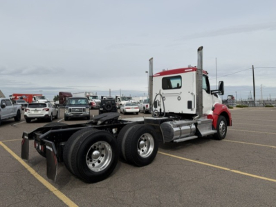 Kenworth T880 Conventional Daycab tractor with white cab and red accents, rear view showing dual rear axles and frame, no trailer attached.