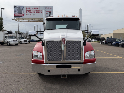 Kenworth T880 conventional daycab front view showing large chrome grille and bumper with red fenders.