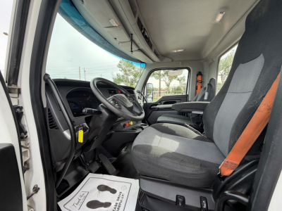 Kenworth T880 truck cab interior view showing steering wheel, driver seat with orange seat belt, dashboard, and center console, gray fabric seats and overhead storage.