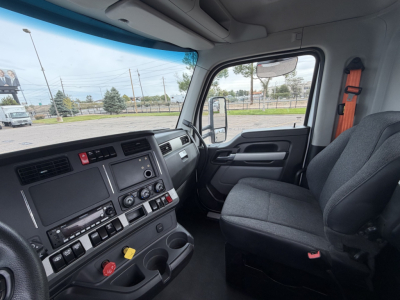 Cab interior of a 2023 Kenworth T880 conv daycab showing dashboard controls, steering wheel, and passenger seat.