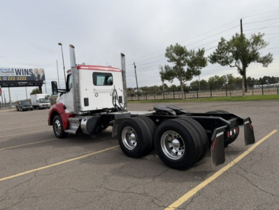 Kenworth T880 tractor rear/side view showing tandem rear axles and fifth wheel mounting, with cab in red and white.