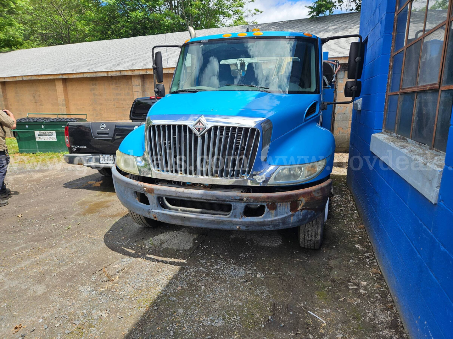 Front view of a blue 2004 International 4300 service/util ity truck showing grille, bumper, and headlights.