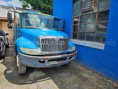 Blue 2004 International 4300 service/utility truck parked next to a blue building; front grille and bumper visible; stock number 32136-62 and VIN 1HTMMAAN64H678543 present in listing text overlay.