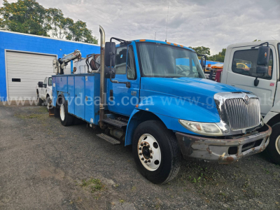 2004 International 4300 utility truck in blue, front view with service bed and crane attachment, showing worn bumper and dual rear wheels.
