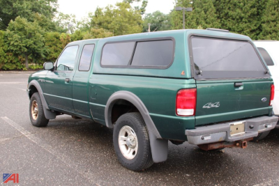 Ford Ranger pickup with extended cap showing rear and driver-side quarter panel in green, 2000 model year, in a parking lot.