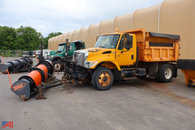 International WorkStar 7300 dump truck with plow and spreader attached, yellow cab and orange dump body, parked outdoors.