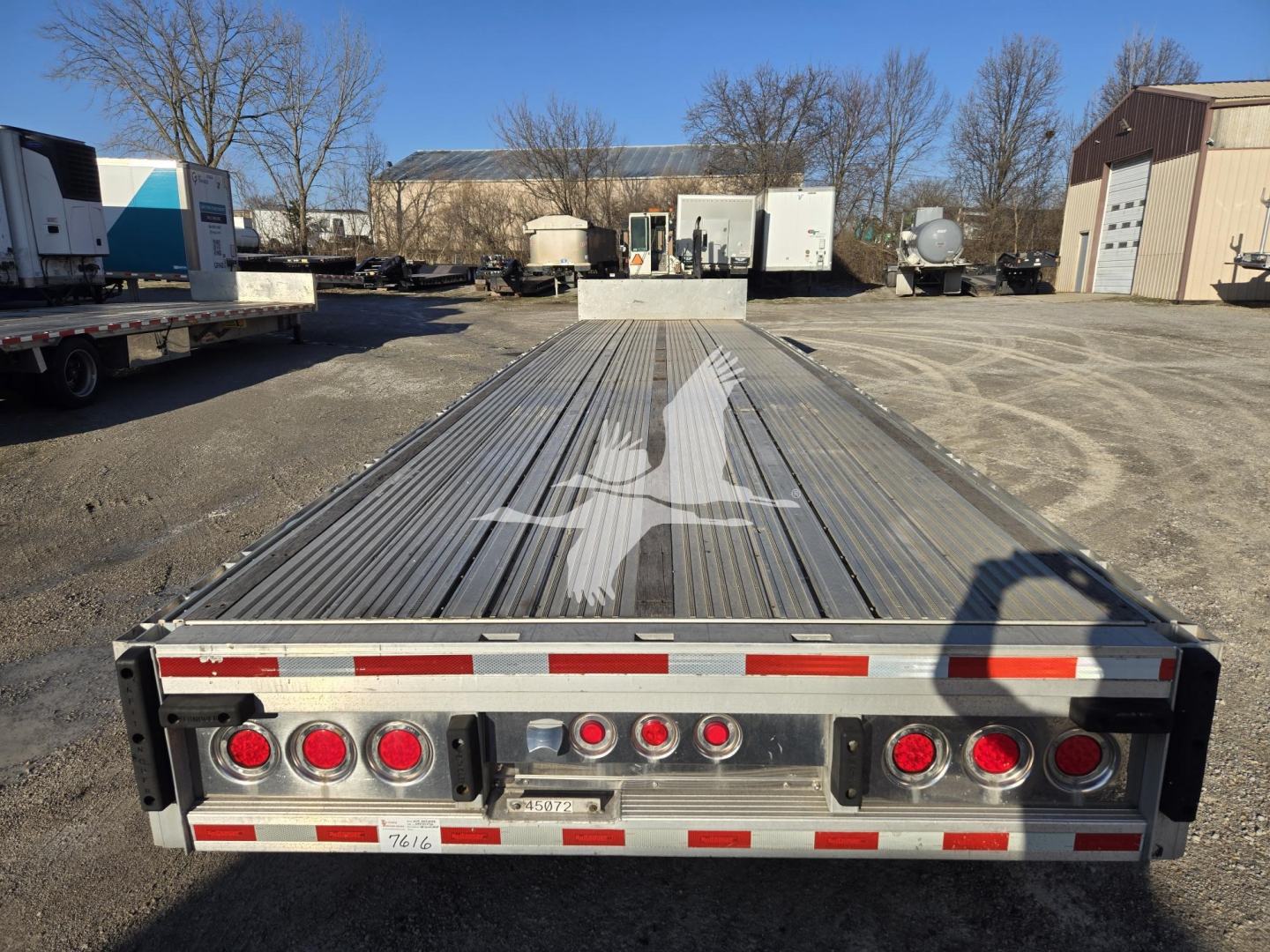 Dropdeck trailer bed with via rear lights and reflective tape, logo of bird on the deck, rear bumper with multiple circular lights.