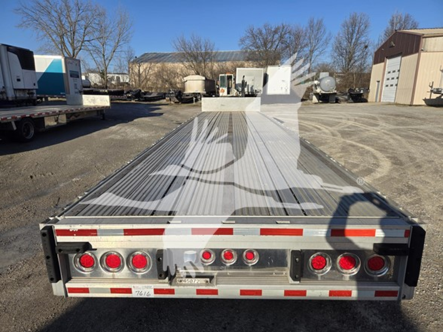 Trailer rear view showing a 2019 Reitnouer Dropmiser drop deck trailer with LED taillights, red reflectors, and steel deck.