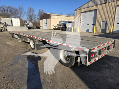 2019 Reitnouer Dropmiser flatbed trailer showing long flat deck, dual rear wheels, and reflective red/white safety markings along sides and rear.