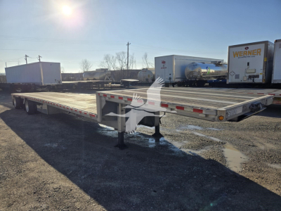 Drop deck trailer (flatbed) with extended gooseneck area, low ground clearance, and landing legs visible. Side rails and reflective tape along edges; background shows other trailers.