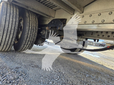 Drivetrain area of a trailer showing tandem wheels, suspension, and undercarriage components with bolts and framing visible.