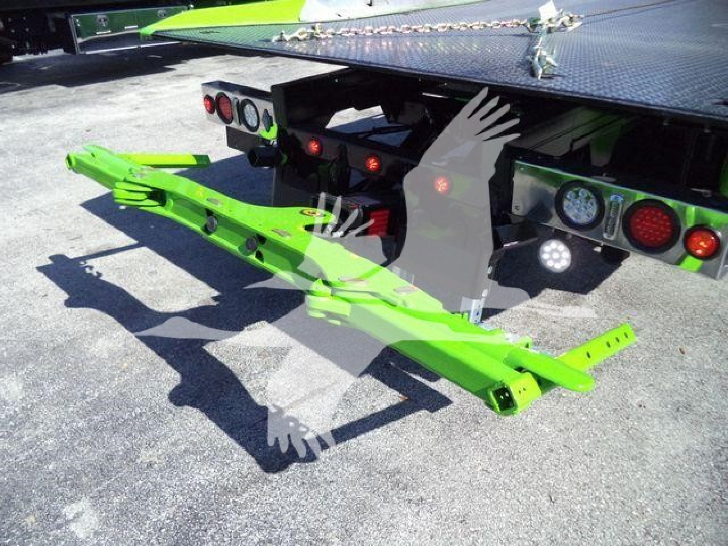 Green tow hitch or rollback equipment attached to the rear of a Kenworth truck, with bright green frame and mounting brackets.
