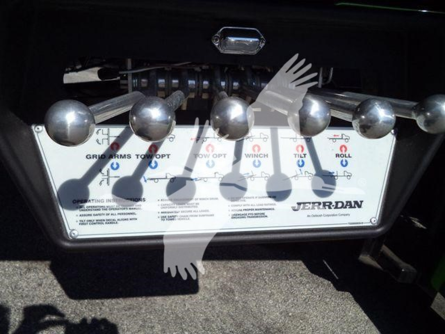 Tow truck stake body tilt mechanism control panel with knobs and levers, Jerr-Dan branding visible on lower right, metallic surface with labels.