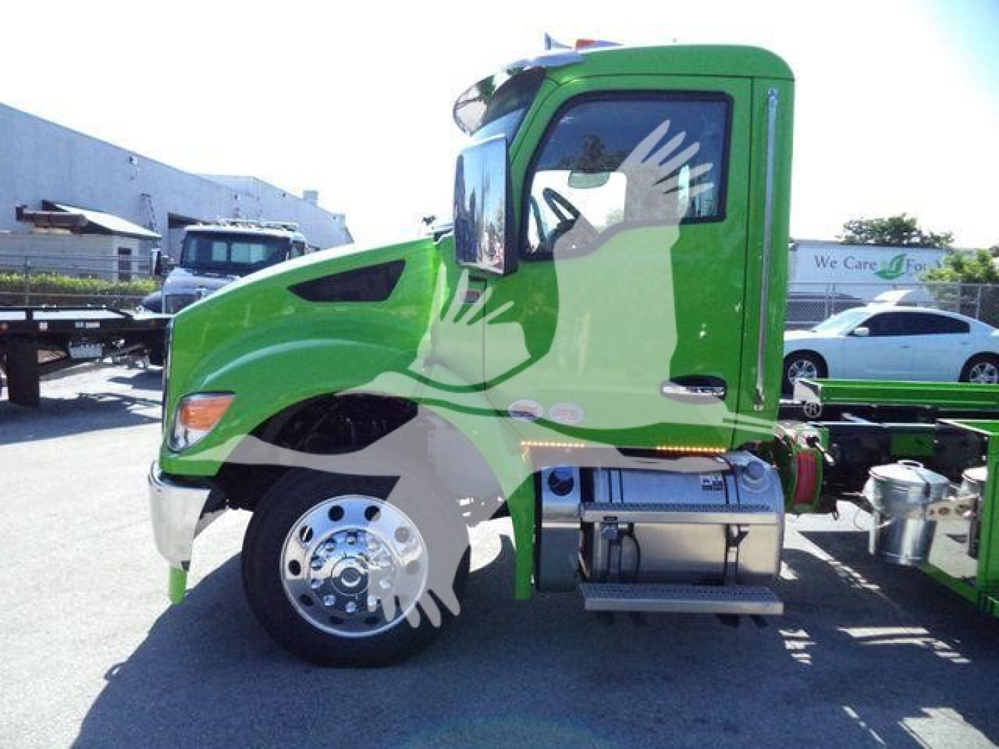 Front side view of a green Kenworth T280 truck cab with chrome fuel tanks and wheel, shown in a dealership lot.